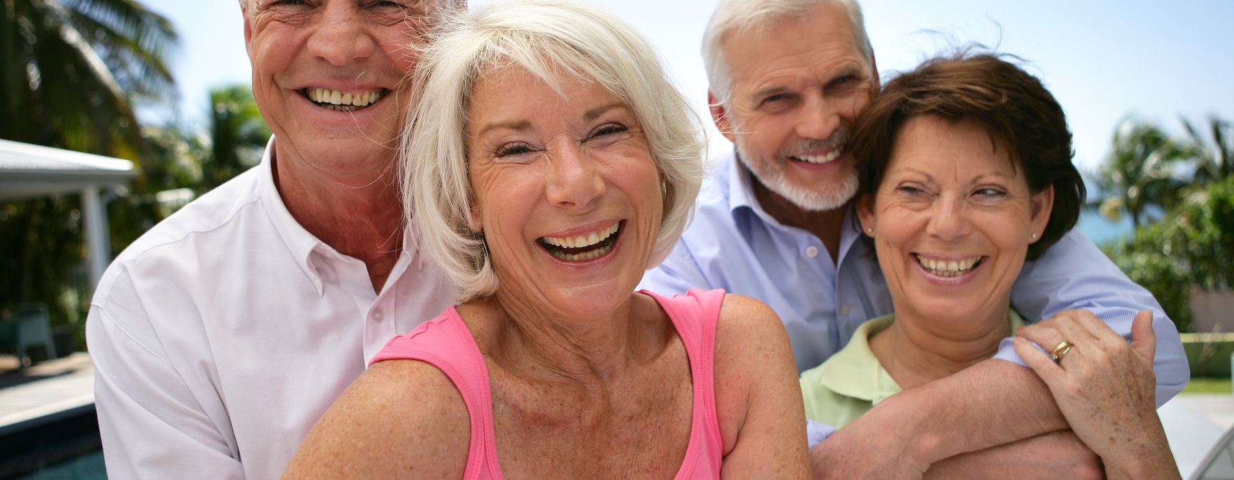 Four residents laughing and hugging outside near Encore at Tradition 55+ community in Port St Lucie, Florida.